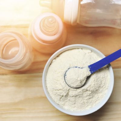 milk powder in spoon with can and baby bottle milk bowl on woode